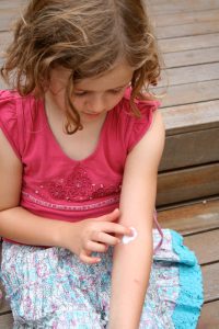 Young girl applying cream.