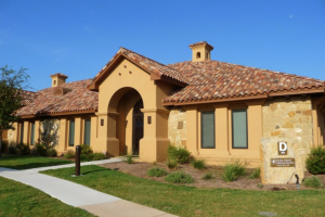 A Mediterranean-style medical office building with a terracotta roof and arched entrance under a clear sky.