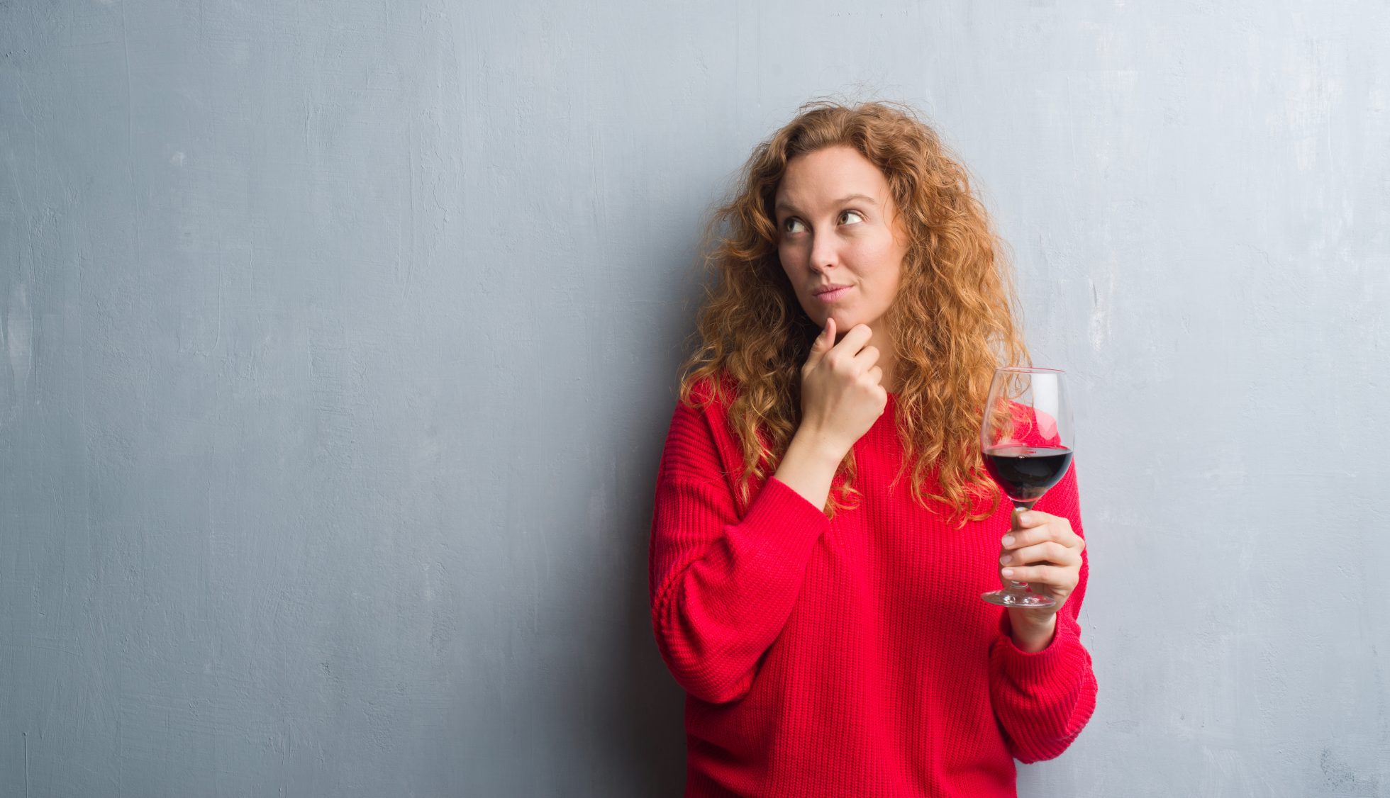 Woman thinking about rosacea triggers while drinking red wine
