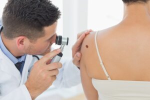 Doctor examining skin cancer on back of woman