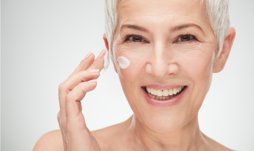 Happy senior woman using skin care products