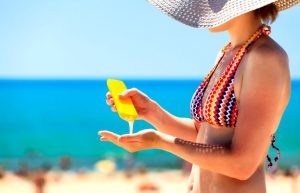 Sunscreen is applied by a woman on a beach.