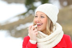 Woman applying lip balm to dry skin