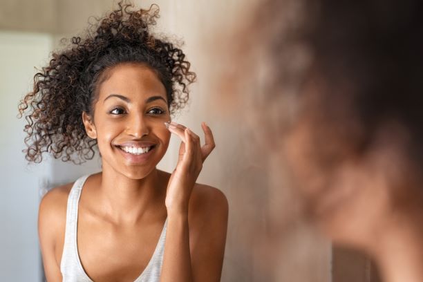 Woman with healthy skin looks in mirror