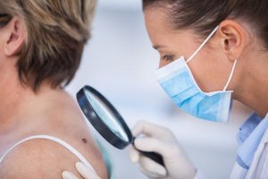 Dermatologist examines woman for skin cancer