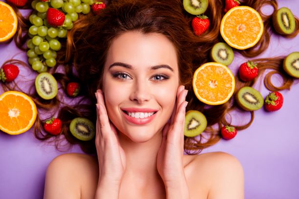 woman with healthy skin surrounded by fruit