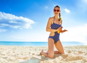 woman on beach applying sunscreen