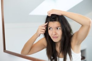 Woman checks scalp for psoriasis vs dandrruff