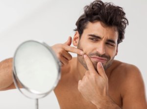 Man looks at beard acne in mirror