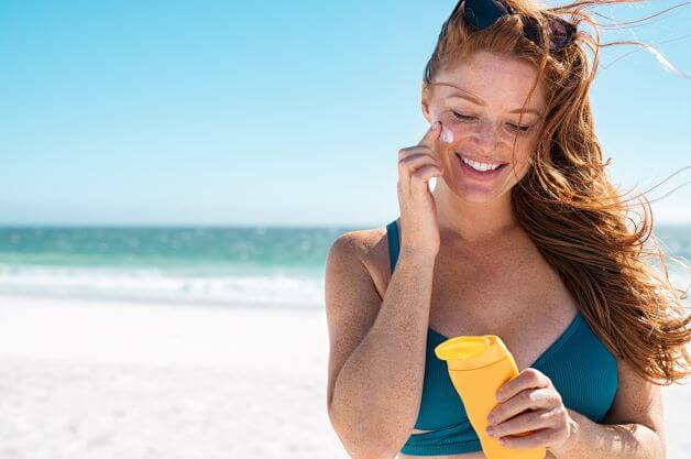 Woman applies sunscreen while tanning