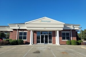 U.S. Dermatology Partners clinic building with a brick facade, white columns, and an empty parking lot.