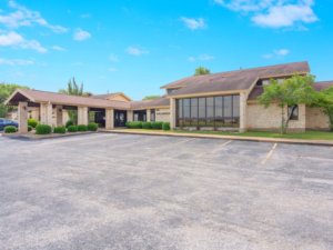 A stone-clad medical office building with large windows, a covered entrance, and an empty parking lot
