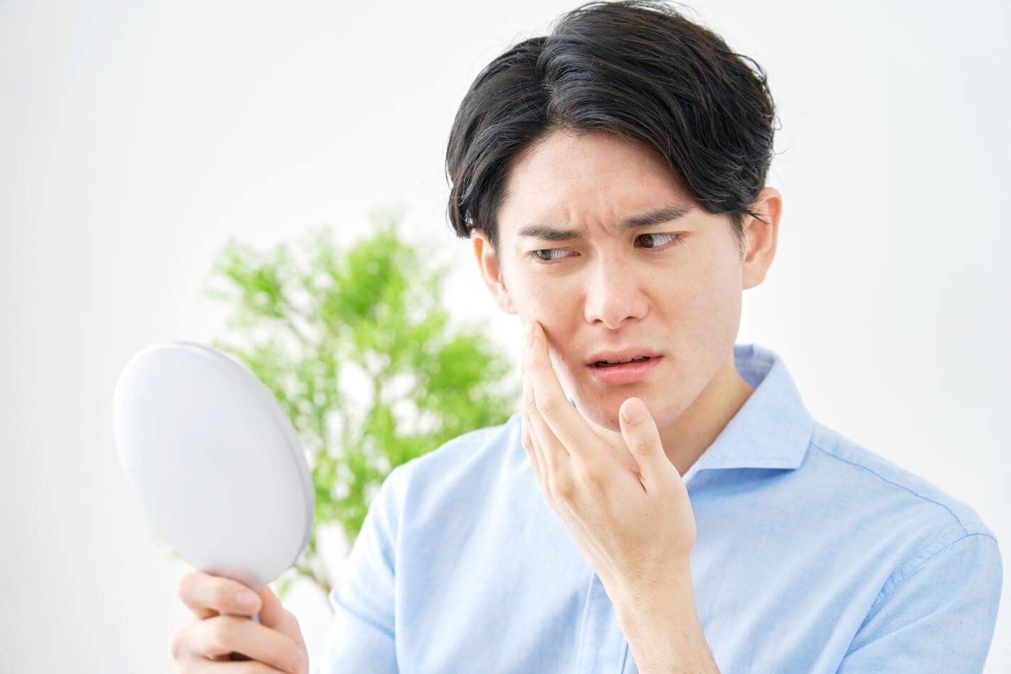 Man looking at acne in the mirror - why is acne more common in the summer months