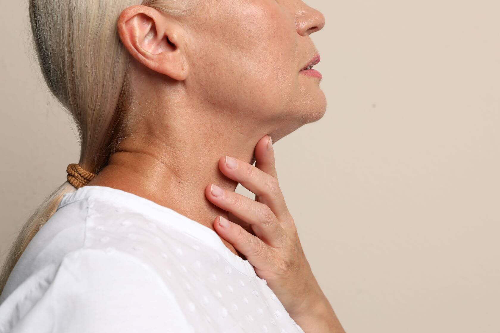 woman considers how to improve the appearance of an aging neck
