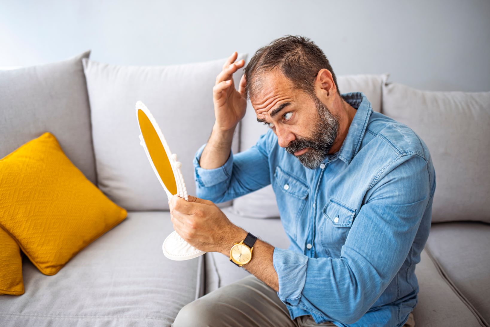 Man with hair loss looks in the mirror